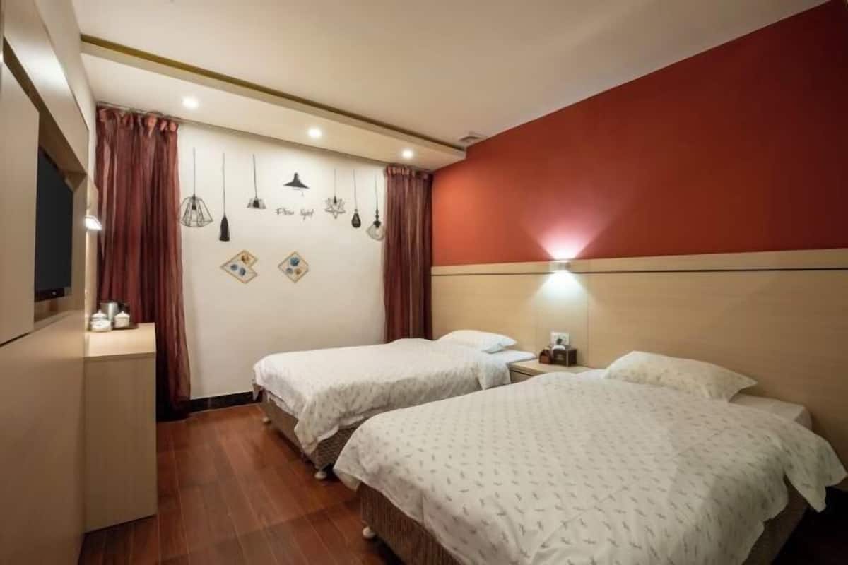 A hotel room with two beds, a desk, a dresser, and a wall with hanging lights and decorative items.
