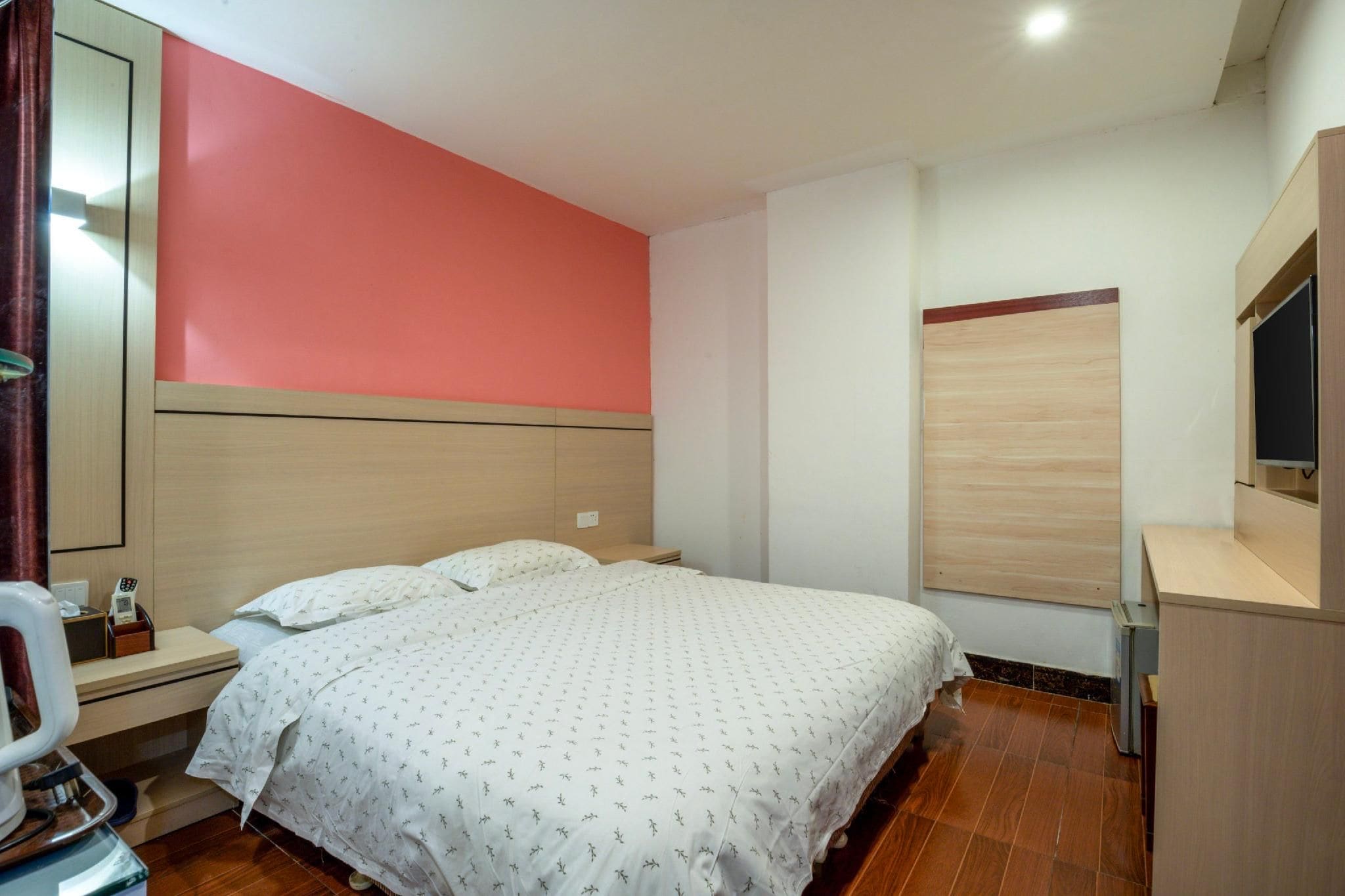A hotel room with a bed, bedside table, and a mirror.