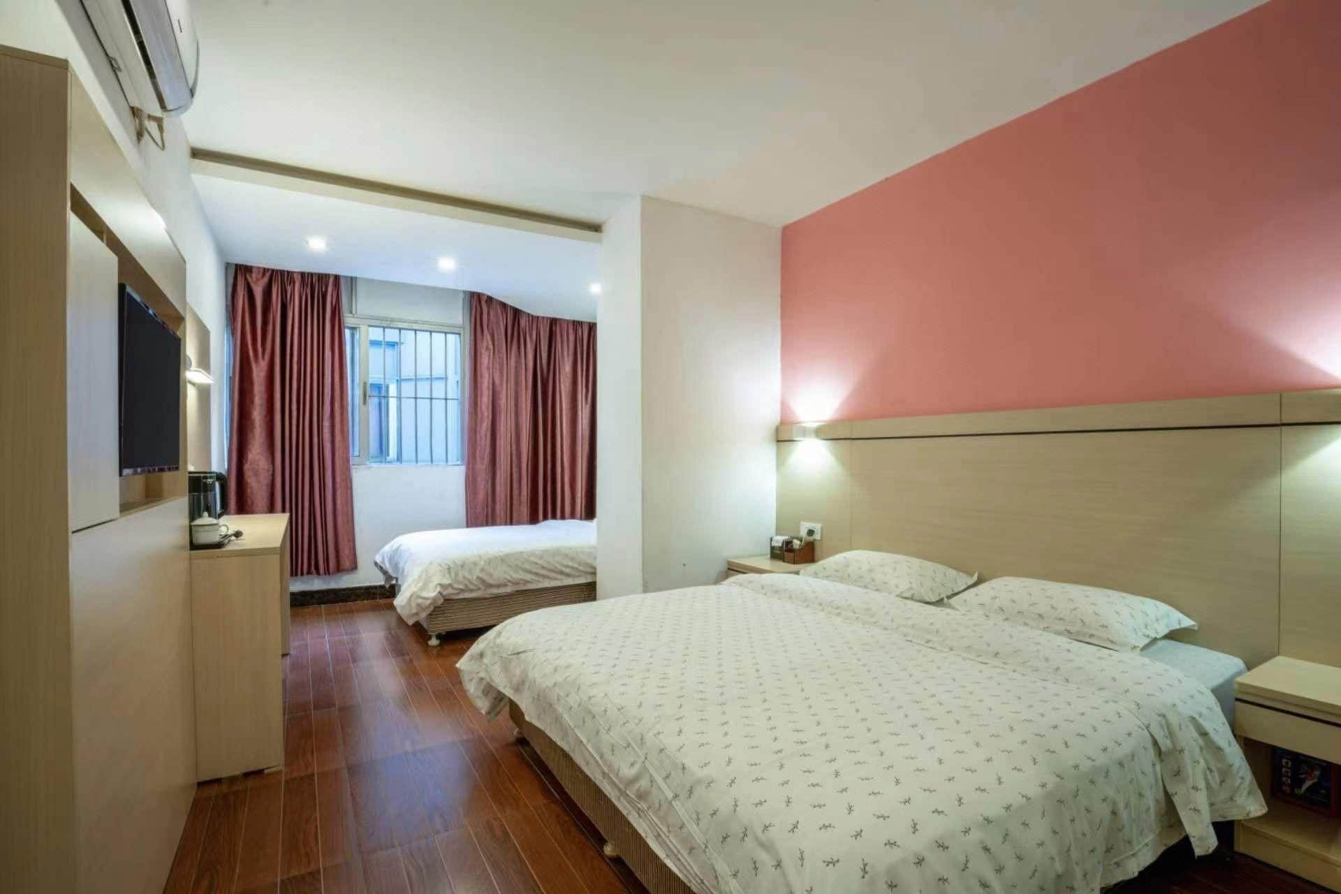Een hotelkamer met twee bedden, een bureau, een televisie en een raam met gordijnen.