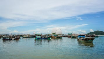 A harbor with multiple boats docked, a large spherical structure, and a hilly landscape in the background.
