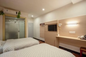A hotel room with two beds, a desk with a chair, a small window, a wall-mounted phone, and an air conditioning unit. - Longxiang Hotel (Zhuhai)