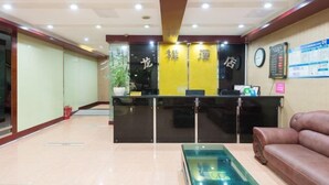A hotel reception area with a reception desk, a clock, and a bulletin board. - Longxiang Hotel (Zhuhai)