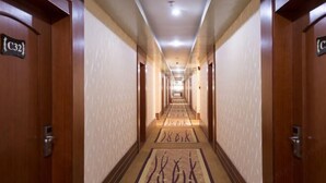 A hotel hallway with wooden doors, numbered room signs, and a carpeted floor. - Longxiang Hotel (Zhuhai)