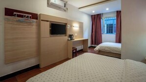 A hotel room with a bed, a TV, a desk, and a wardrobe. - Longxiang Hotel (Zhuhai)