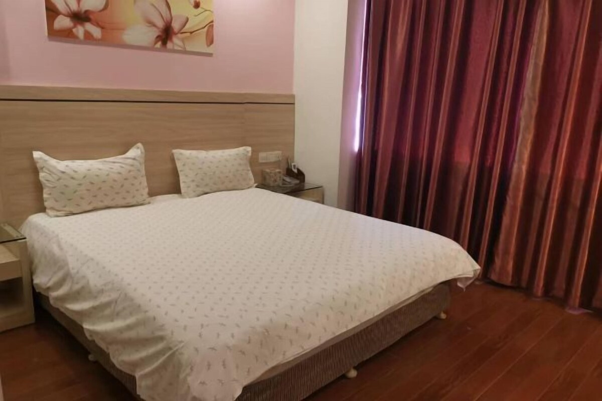 A neatly made bed with a patterned bedspread, a wooden headboard, and a nightstand with a lamp.
