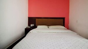 A bedroom with a single bed, a nightstand, and a red accent wall. - Longxiang Hotel (Zhuhai)