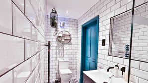 A modern bathroom with white subway tiles, a blue door, a white sink, and a hanging plant. - Luxury Boutique 2 Bed Apartment in the heart of Bowness on Windermere (Bowness-on-Windermere)