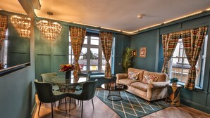 A cozy living room with a sofa, a coffee table, and a dining area with chairs and a table. - Luxury Boutique 2 Bed Apartment in the heart of Bowness on Windermere (Bowness-on-Windermere)
