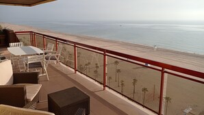 Un balcon donnant sur la plage, aménagé avec des fauteuils et une table en osier.