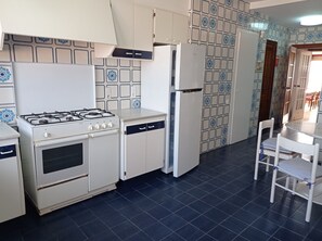 Een koelkast, een microgolfoven, een oven, kookgerei, borden en bestek