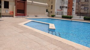 Une piscine dotée d’une terrasse carrelée, entourée d’immeubles d’habitation.