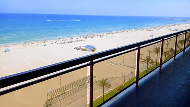 Une vue sur la plage depuis un balcon, avec un ciel dégagé.