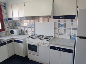 Een koelkast, een microgolfoven, een oven, kookgerei, borden en bestek