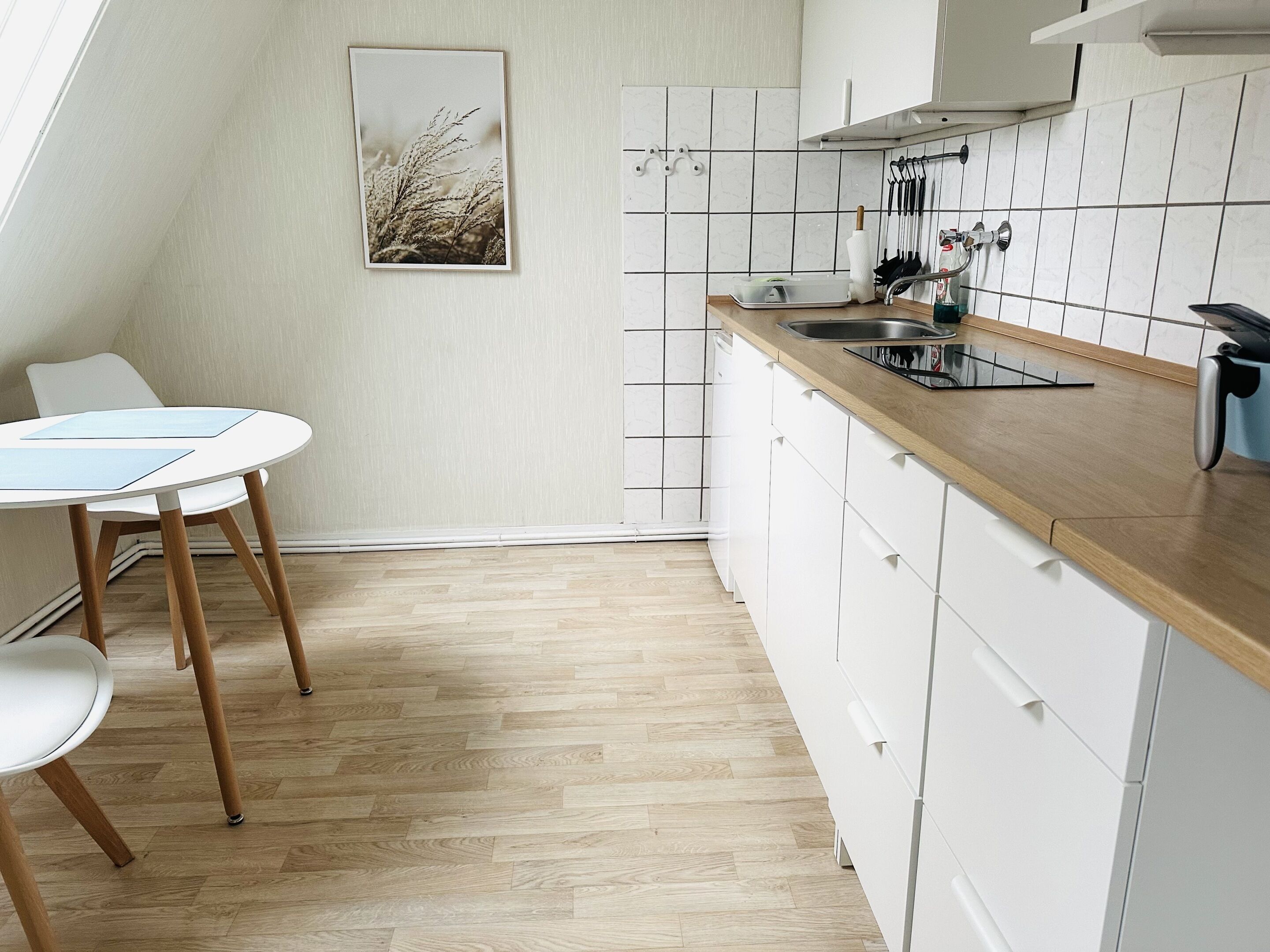 Een moderne keuken met witte kastjes, een houten aanrecht en een eethoek met een tafel en stoelen.