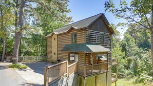 Een houten chalet met balkon, omgeven door bomen.