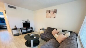A modern living room with a grey sofa, a round coffee table, and a painting on the wall. - Windward West 30 - Pool & 5 Minutes from the Beach (Cocoa Beach)