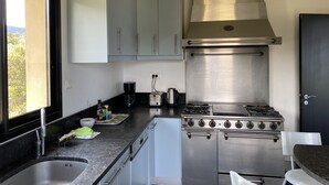 Una cocina compacta con estufa a gas, horno empotrado y ventana con vistas al exterior.
