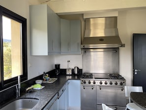 Une cuisine compacte équipée d’une cuisinière à gaz, d’un four encastré et d’une fenêtre donnant sur l’extérieur.