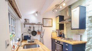 Eine kompakte Küche mit Holzausziehtisch, Edelstahlspüle und eingebautem Backofen.