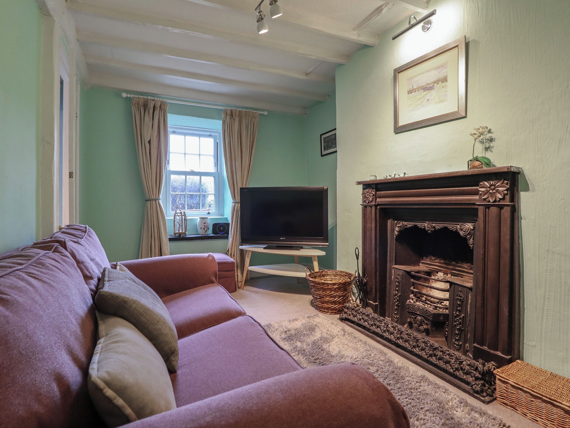 A living room with a sofa, a fireplace, a television, and a window with curtains.