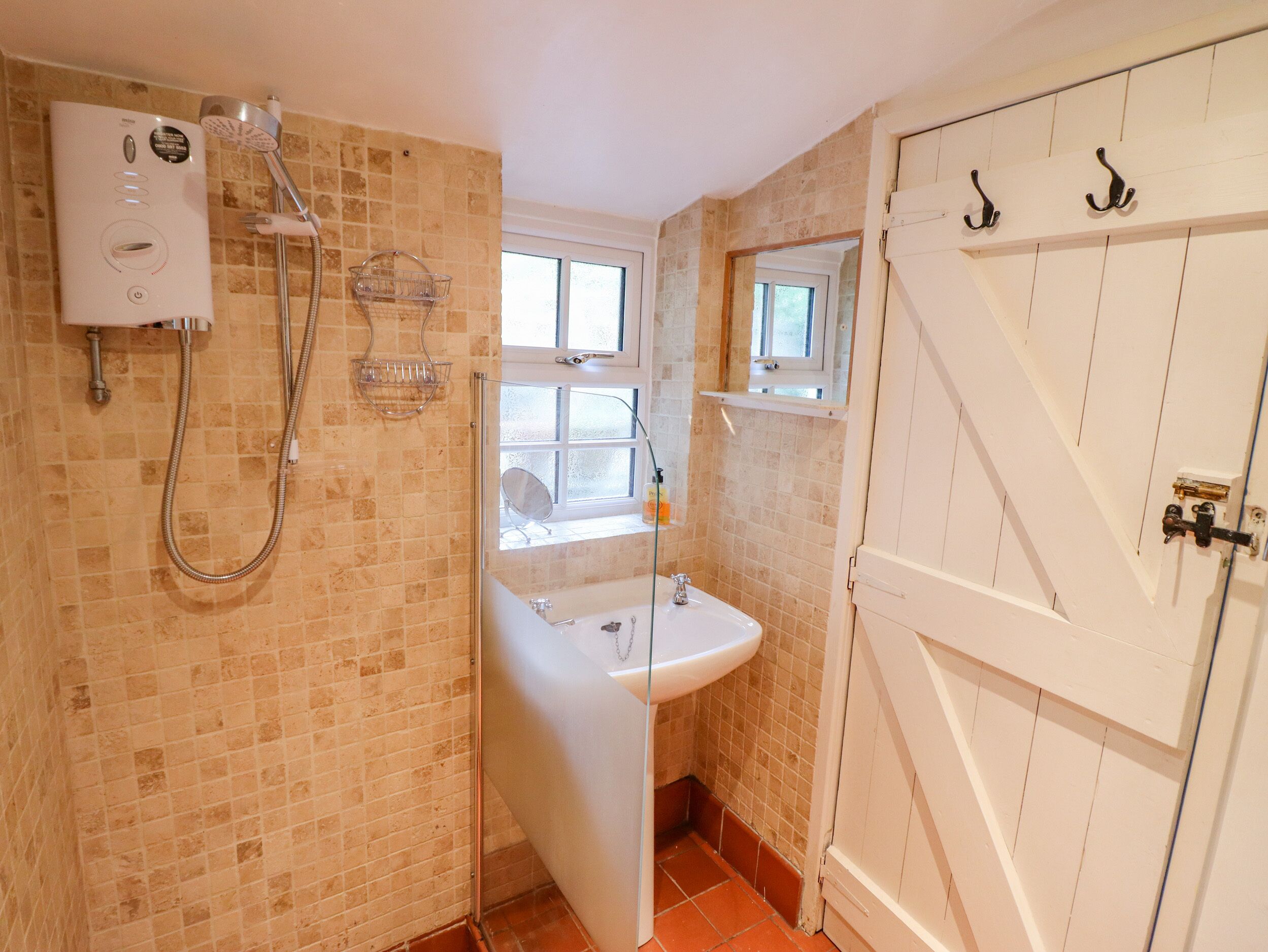 A bathroom with a shower, a sink, and a window.