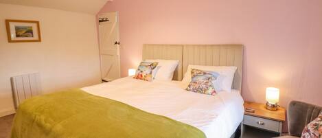 A bedroom with a bed, a nightstand, a chair, and a lamp.