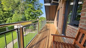 Un patio in legno con ringhiera metallica, un muro in mattoni e una finestra.
