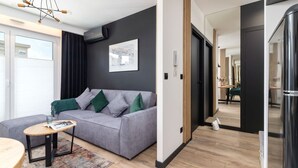 A modern living room with a grey sofa, a small wooden coffee table, and a black-framed picture on the wall.