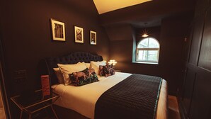 A bedroom with a large bed, a bedside table, a window with a view, and framed pictures on the wall. - Luxury Boutique 2 Bed Apartment in the heart of Bowness on Windermere (Bowness-on-Windermere)