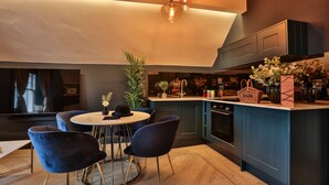 A modern kitchen with a round dining table, dark blue chairs, and pendant lighting. - Luxury Boutique 2 Bed Apartment in the heart of Bowness on Windermere (Bowness-on-Windermere)