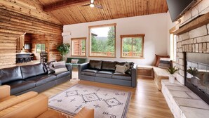 A log cabin interior with a fireplace, leather sofas, and a stone fireplace surround. - Bears Ears Luxury Retreat (Monticello)