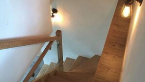 Un escalier en bois, doté d’une rampe et de luminaires fixés au mur.