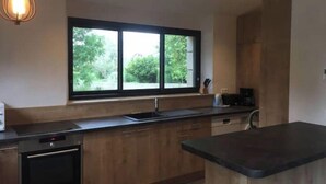 Une cuisine moderne dotée d’une grande fenêtre, de meubles en bois, d’un plan de travail noir et d’un four encastré.