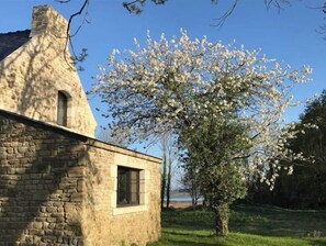 A stone building with a small window and a tree with white blossoms in the background. - Maison Jardin Piscine et vue - Logement 3 (Locoal-Mendon)