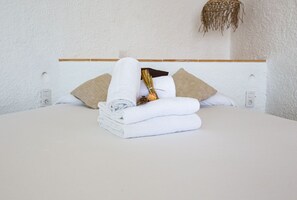 A neatly made bed with white linens and a rolled towel, accompanied by a decorative item and two pillows. - Agi Castell Mar 1003 Apartamento for rent in Roses Girona. (Roses)