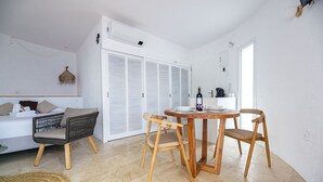 A modern, well-lit room with a sofa, two wicker chairs, a wooden dining table, and a kitchen area with a coffee machine. - Agi Castell Mar 1003 Apartamento for rent in Roses Girona. (Roses)