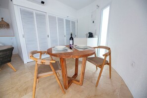 A dining area with a round wooden table, two wooden chairs, and a bottle of wine.