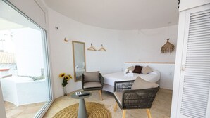A modern bedroom with a bed, a chair, a small table, and a mirror. - Agi Castell Mar 1005 Apartamento for rent in Roses Girona. (Roses)