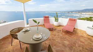 Une terrasse avec une table dressée pour deux personnes, deux fauteuils et un pot de fleurs.