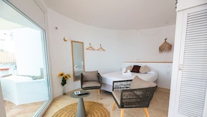 A modern room with a bed, two chairs, a small table, a mirror, and a hanging light fixture. - Agi Castell Mar 1009 Apartamento for rent in Roses Girona. (Roses)
