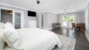Une chambre à coucher avec un grand lit, un ventilateur de plafond, une télévision, un piano et une vue sur l’extérieur.