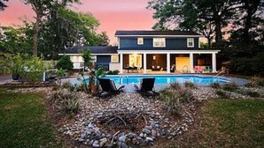 Une maison à deux étages avec une piscine, un espace extérieur aménagé pour se détendre et un jardin bien entretenu.
