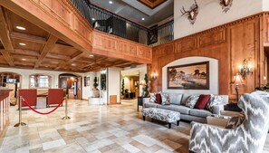 Eine geräumige Lobby mit hoher Decke, Holzvertäfelung, einer imposanten Treppe und einem großen Gemälde.