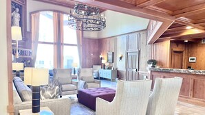 A spacious living area with a large chandelier, comfortable seating, a fireplace, and a view of the outdoors. - 231 | Premium Escape | 2Q Near Sundance + Park City (Midway)