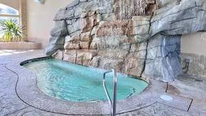 Zona de piscina con pared rocosa y una cascada.