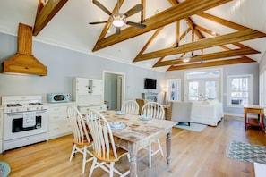 Enjoy meals in the kitchen with a central island and dining table for four, leading to a cozy living area with a sofa and TV.