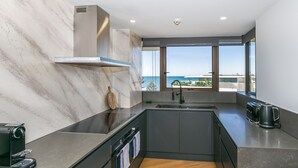 Una cocina moderna con una isla grande, horno empotrado y vistas al océano.