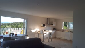 A modern kitchen with white cabinets, a microwave, and a window overlooking a balcony.