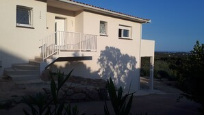 A two-story house with a white exterior, a balcony, and a view of the surrounding landscape. - PRETTY VILLA, independent, close to the beach, the mountains, the shops! (VENTISERI)