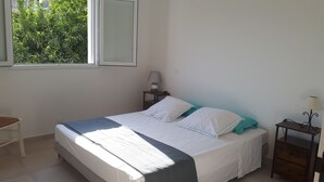A bedroom with a bed, a nightstand, a lamp, and a window with a view of greenery. - PRETTY VILLA, independent, close to the beach, the mountains, the shops! (VENTISERI)